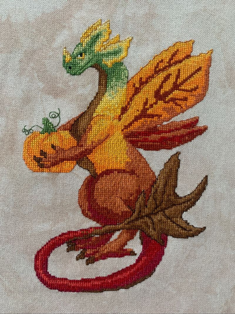 Embroidered dragon holding a pumpkin on fabric