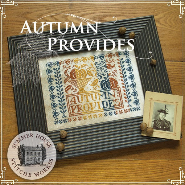 Cross-stitched piece with 'Autumn Provides' text on a wooden surface, featuring Summer House Stitche Works branding.