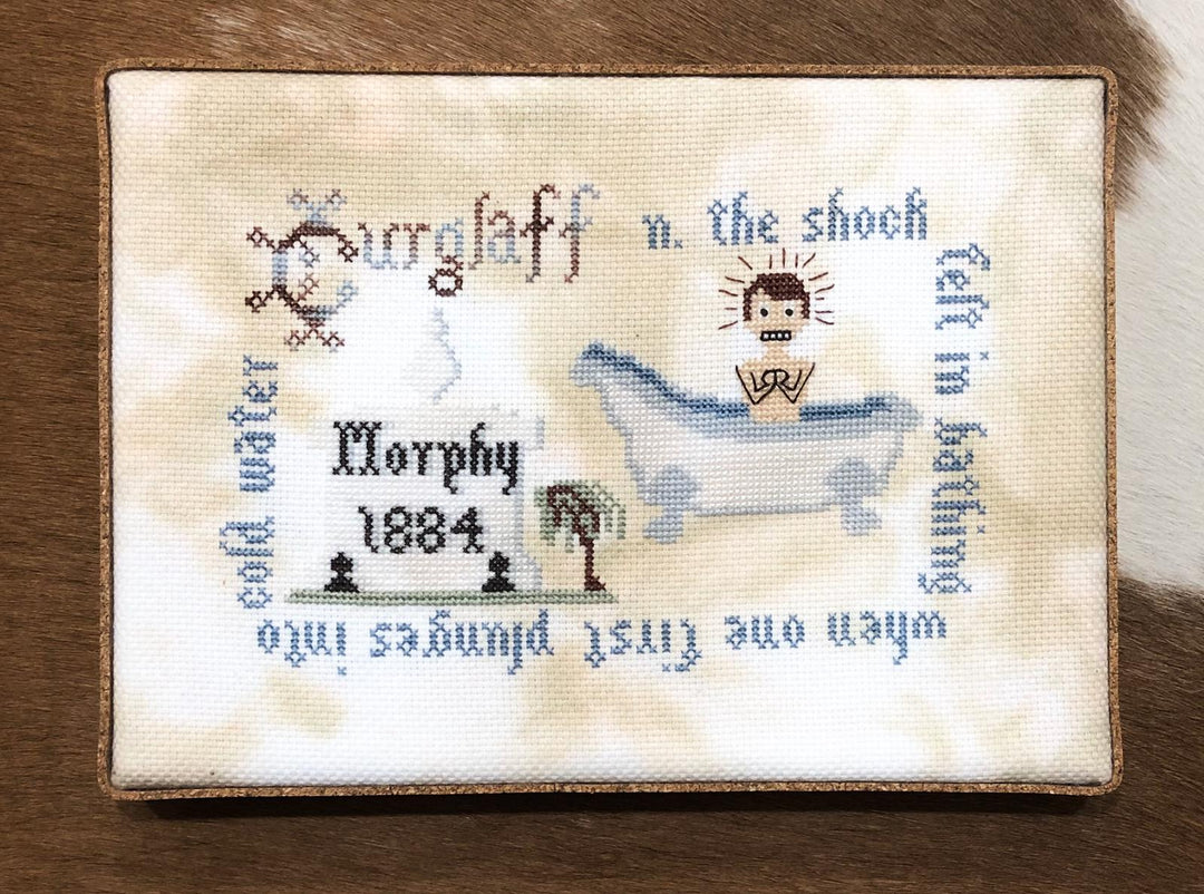 A section of a needlepoint fabric with a literary theme, featuring the word 'Curglaff' and phrases related to water and bathing, stitched in various colors on a beige background.