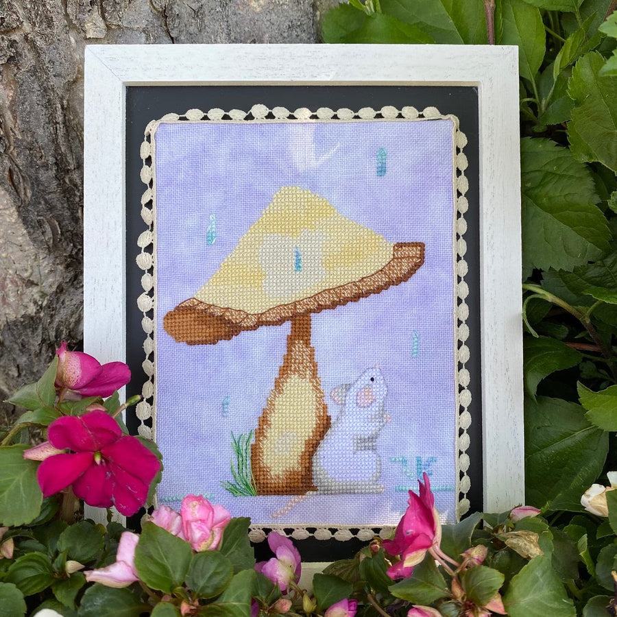 Framed cross-stitched picture of a mushroom and mouse surrounded by flowers and leaves