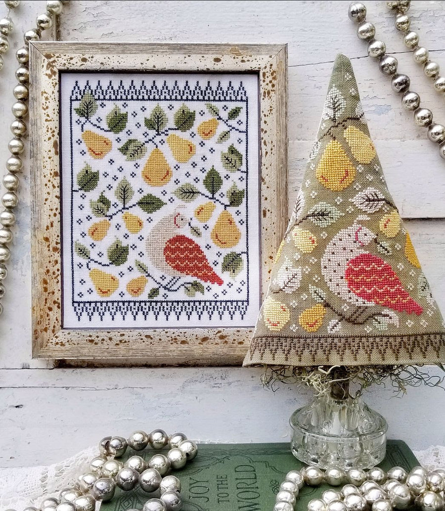 A cross-stitching pattern depicting a bird and tree design, displayed both as a flat sampler and as a three-dimensional tree-shaped finished product, alongside decorative beads and fabric.
