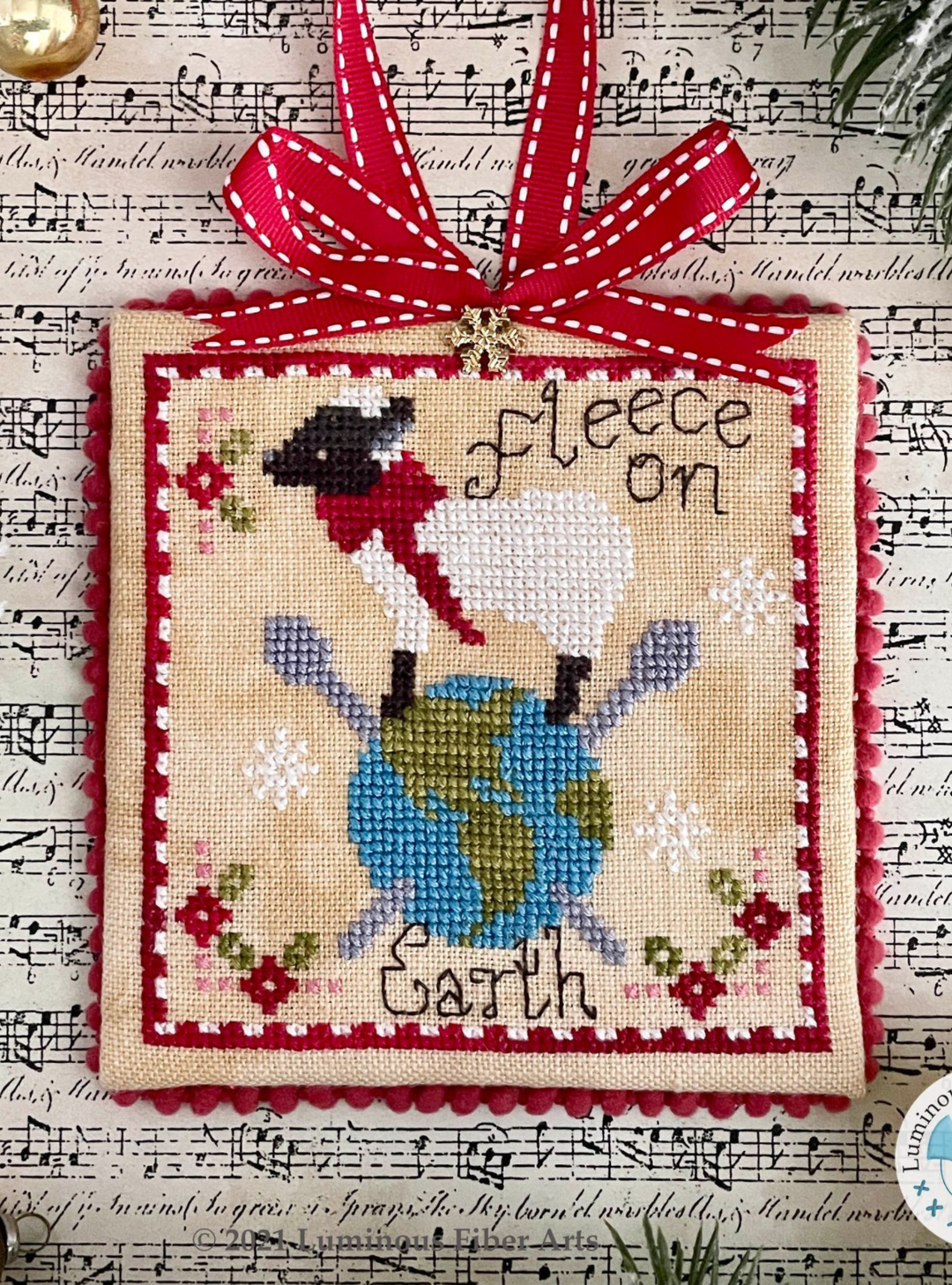 Decorative cross-stitched piece with a reindeer design on a sheet music background