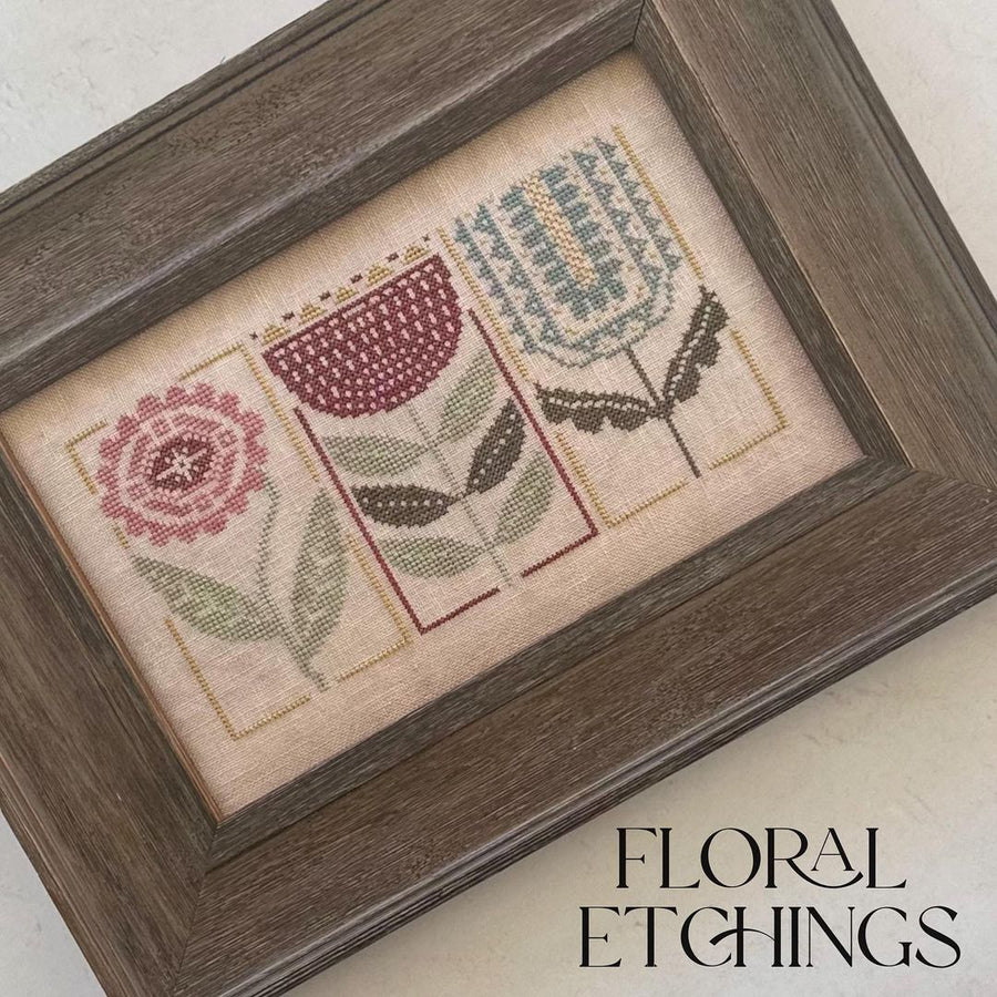 Framed cross-stitched artwork with floral designs on a light background