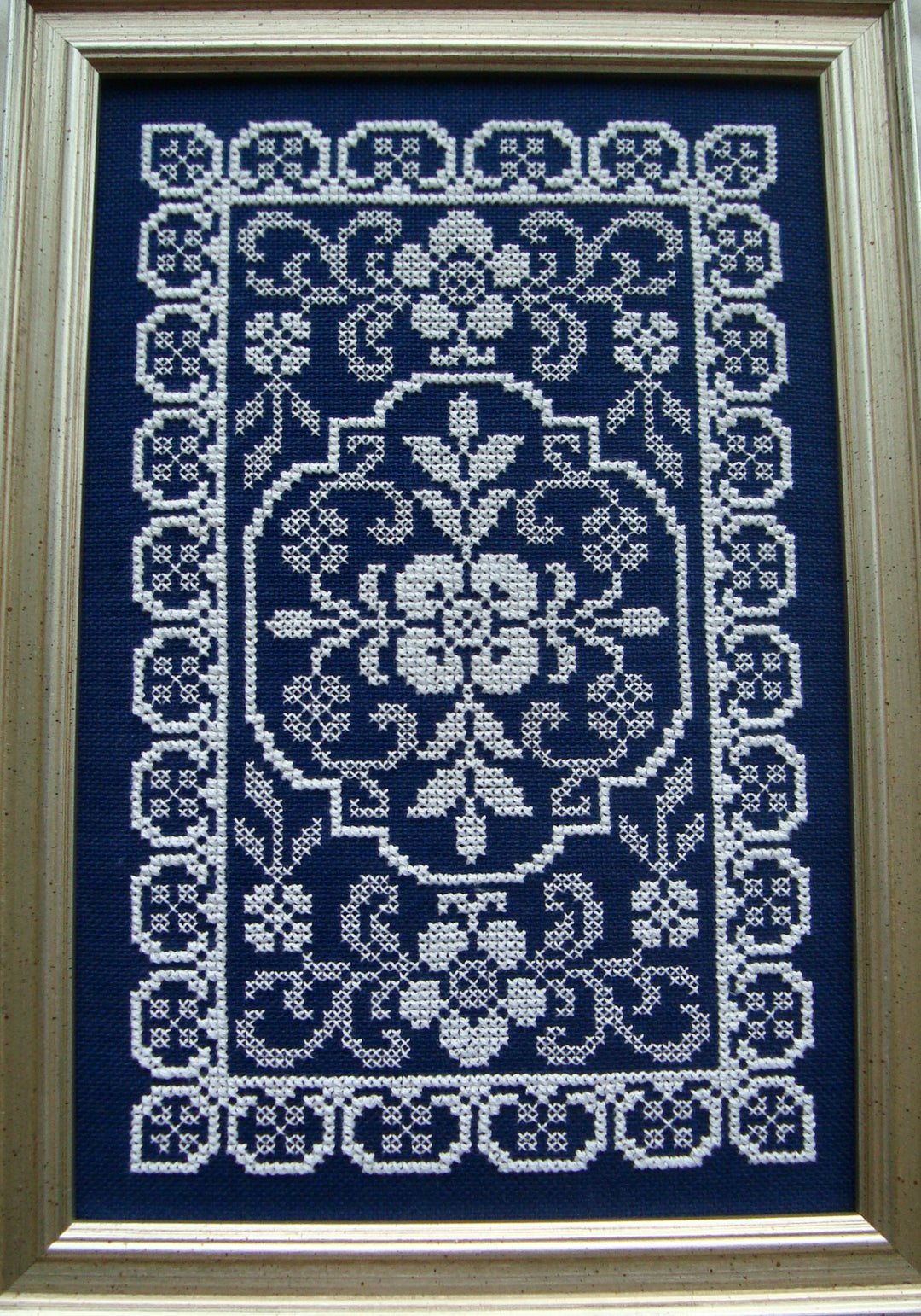 Framed cross-stitched pattern on a blue background