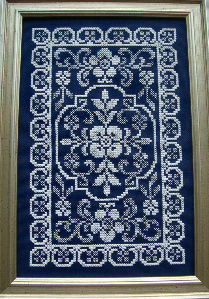 Framed cross-stitched pattern on a blue background