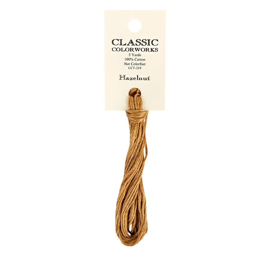 A skein of Classic Colorworks hand-dyed embroidery floss in a beige color, labeled 'Hazelnut'.