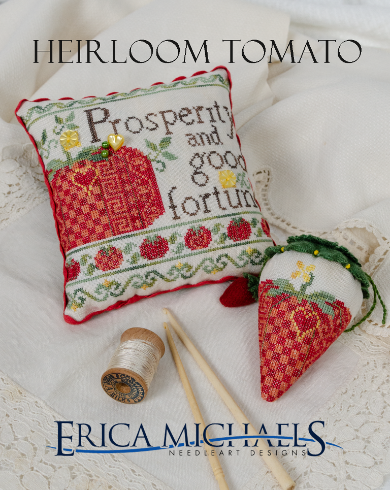 Cross-stitched pillow with 'Prosperity and good fortune' text and a small strawberry-shaped item on a white background, featuring Erica Michaels Needleart Designs.