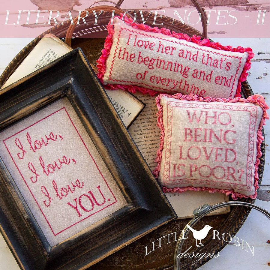 Decorative pillows with embroidered text and a framed print on a wooden surface.