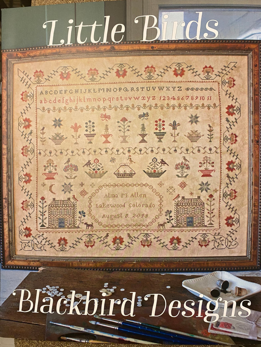 A completed needlepoint artwork titled 'Little Birds' featuring various birds and floral patterns, framed in a wooden frame.