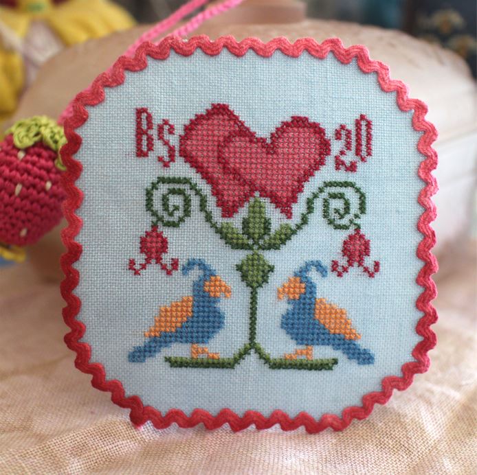 Embroidered heart with birds and text on a light blue background