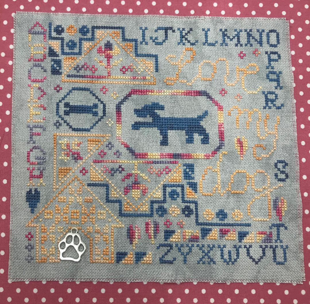 Cross-stitched design with a dog and paw print on a polka dot background