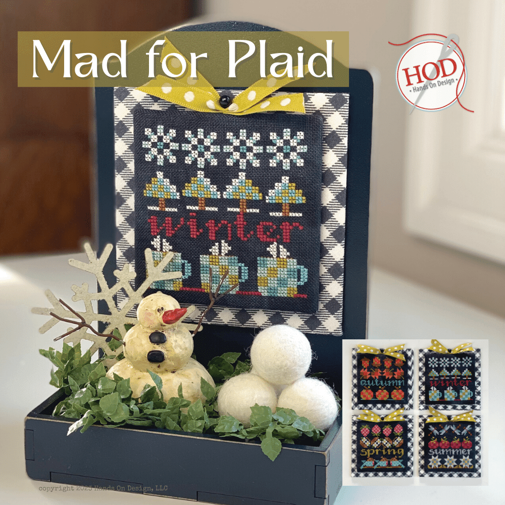 Decorative cross-stitched sign with snowman and snowballs, featuring 'Mad for Plaid' text.