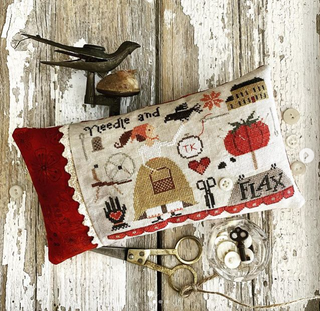 Decorative pillow with cross-stitch patterns on a rustic wooden background