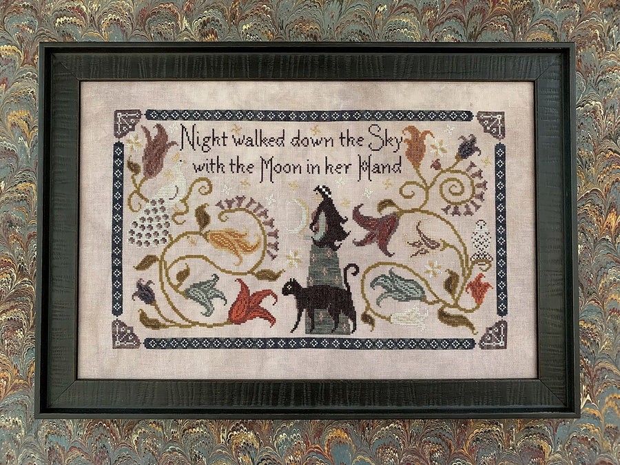 Cross-stitch needlework depicting a moonlit night scene with text, animals, and floral elements on a purple/gray linen background, framed.
