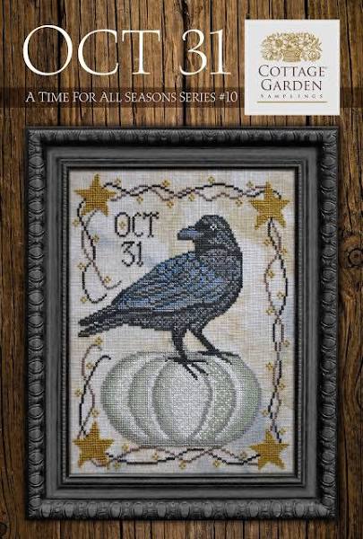 Cross-stitched design of a crow on a pumpkin with 'Oct 31' text, framed on a wooden background with Cottage Garden logo.