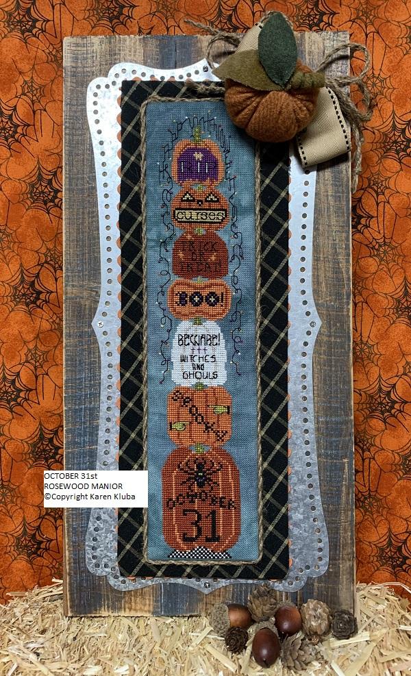 Halloween-themed cross-stitch pattern with pumpkins and text on a wooden frame.