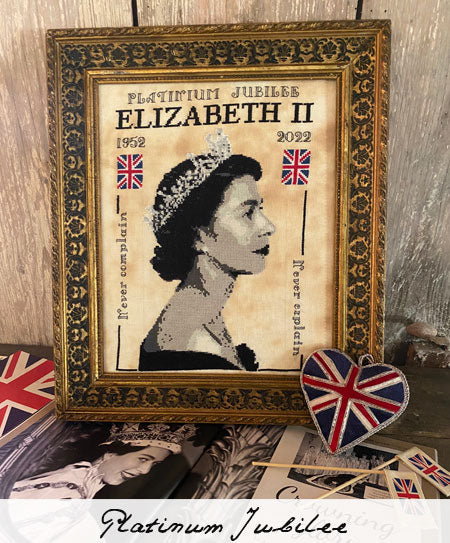 Framed portrait of a monarch with British flags and jewelry on a wooden background
