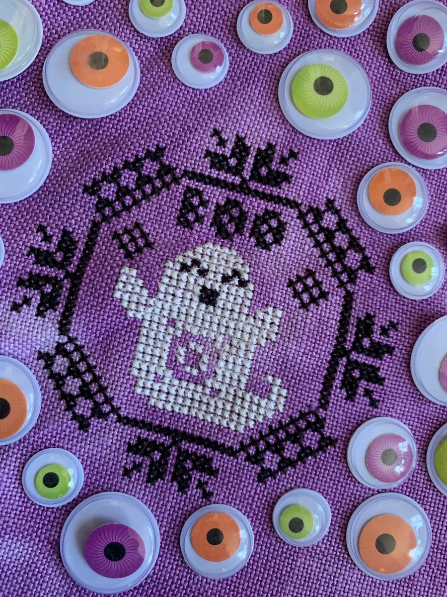 A piece of fabric with a Quaker ghost design, featuring a circular pattern with glow-in-the-dark eyes and a black embroidered outline.