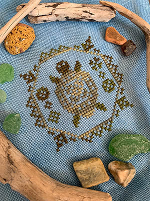 Embroidered design on fabric with natural elements like stones and wood.