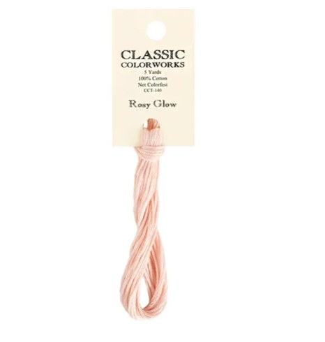 A skein of Classic Colorworks hand-dyed embroidery floss in a pink color, labeled 'Rosy Glow'.