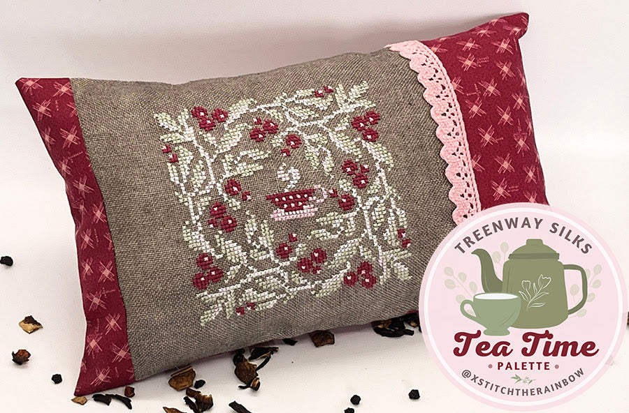 Decorative pillow with embroidered design on a white background, featuring Treenway Silks and xstitch the rainbow branding.