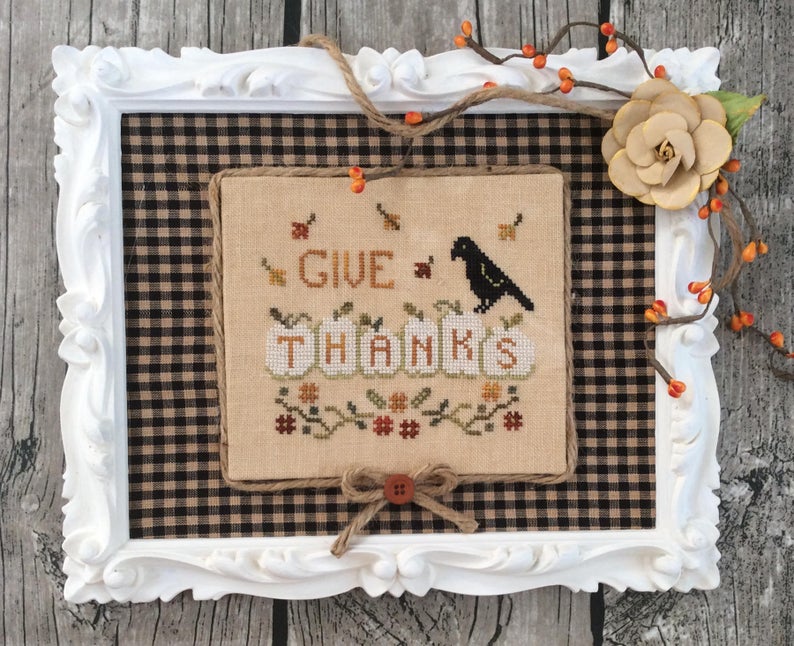framed cross stitch with crow and autumn leaves with text reading give thanks
