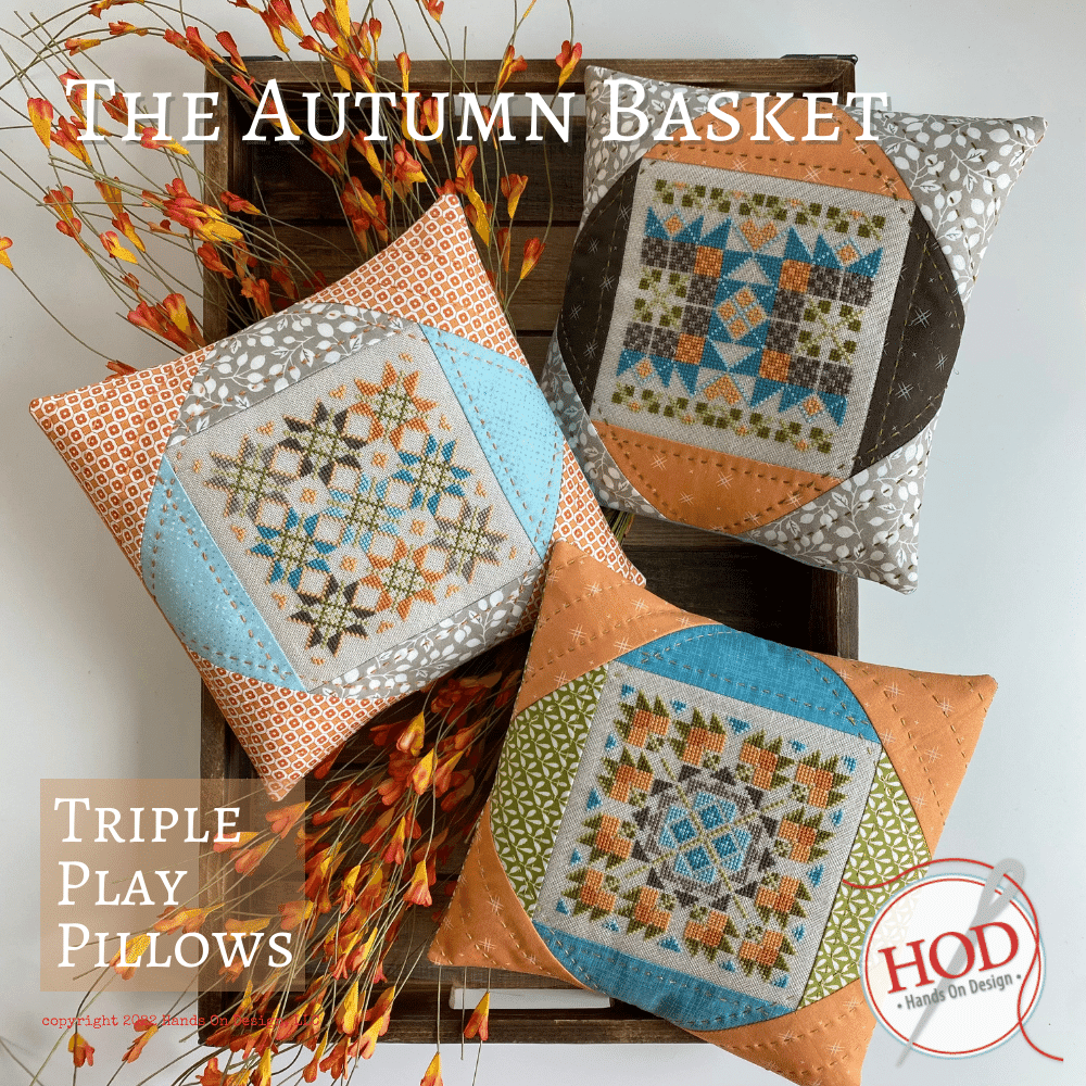 Decorative pillows with autumn-themed patterns on a wooden basket with decorative branches.