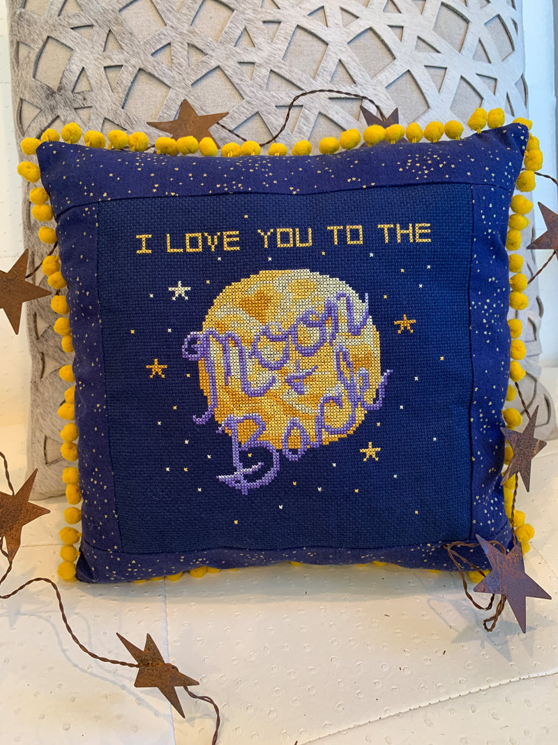 Decorative pillow with embroidered text and moon design on a starry background
