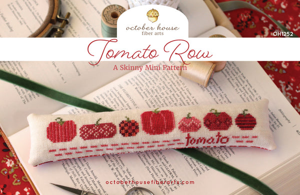 Cross-stitched tomato pattern on a fabric strip with 'October House Fiber Arts' branding.