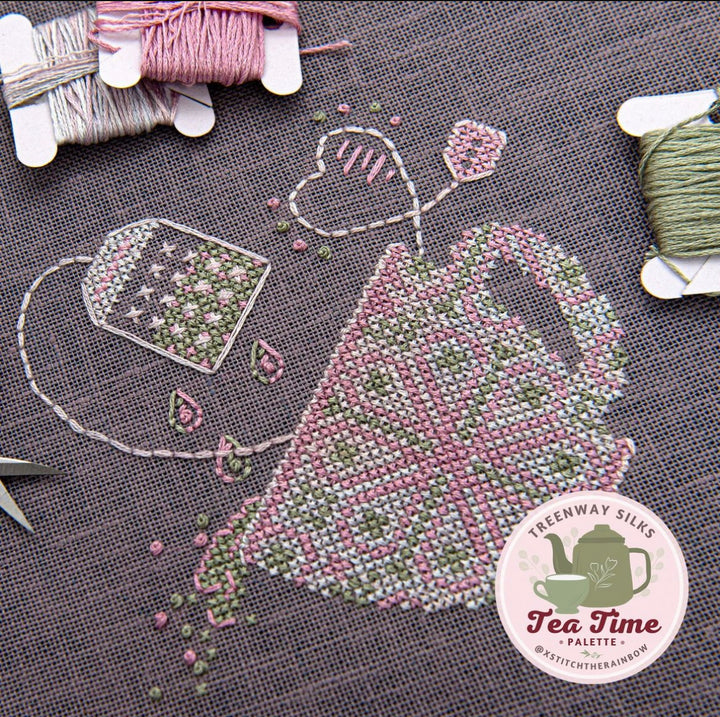 Embroidery kit depicting a tea cup and leaves design, stitched on linen with floss and threads, accompanied by a label with the Tea Time collection logo.
