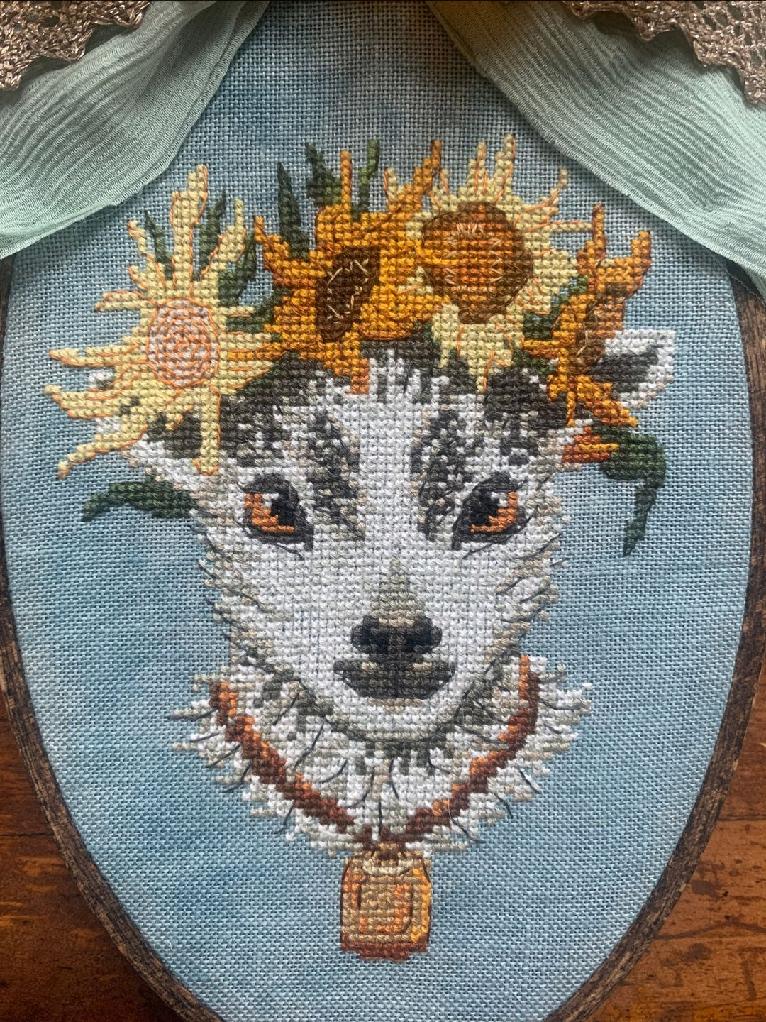 Embroidery of a goat with sunflower headband on a blue background