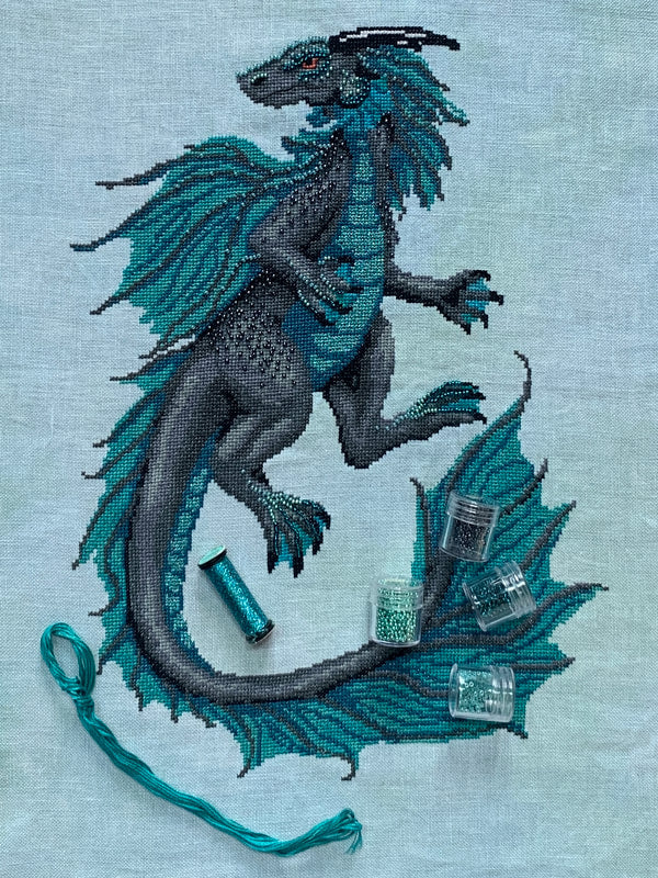 Embroidered dragon design on fabric with thread and beads