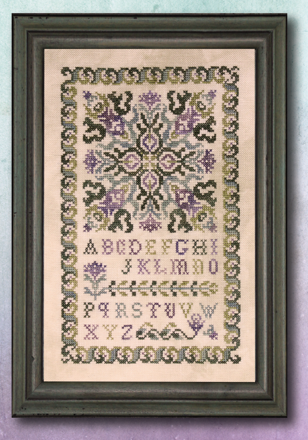 Framed cross-stitched pattern with letters and decorative elements on a light background