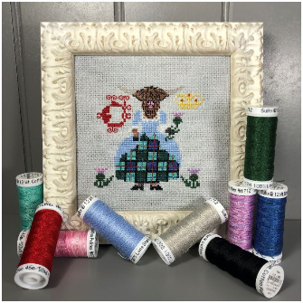 Framed cross-stitched picture of a tortoise and a hare with spools of thread around it.