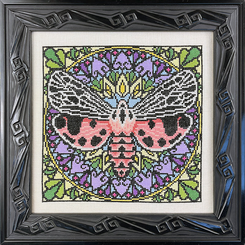 Framed cross-stitched artwork with a colorful butterfly design on a white background