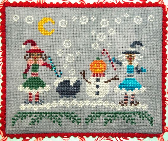 Cross-stitched design of two children and a snowman on gray fabric with red border